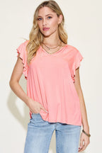 Woman wearing a pink top and blue jeans against a plain background