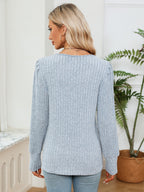 Woman wearing a light blue sweater in a room with a plant