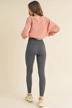 Person wearing a pink sweatshirt and gray leggings on a beige background