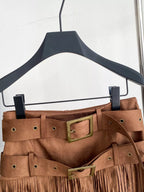 Brown suede skirt with gold buckles on a black hanger against a white background