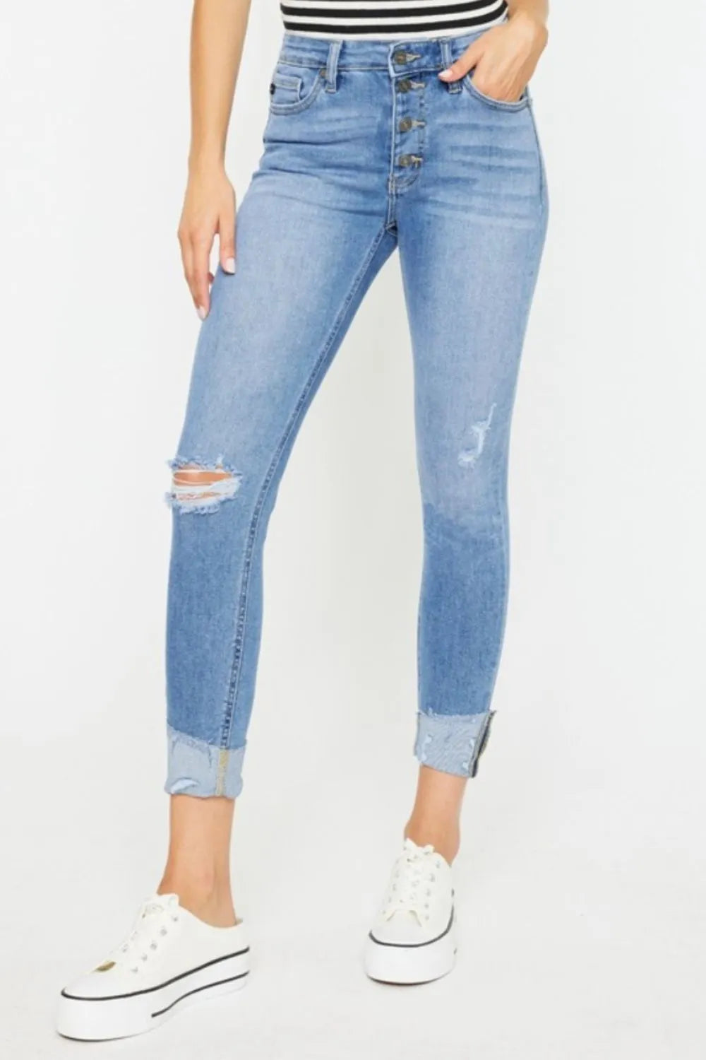 Person wearing light blue distressed jeans on a white background