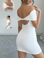 Woman wearing a white dress with cut-out design in a minimalistic room.