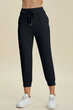Black jogger pants worn by a person on a beige background