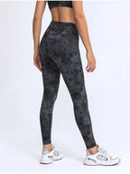 Person wearing black tie-dye leggings on a white background