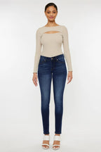 Woman wearing a beige long-sleeve top and blue jeans on a white background