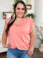 Woman wearing a pink sleeveless top and blue jeans in a home setting