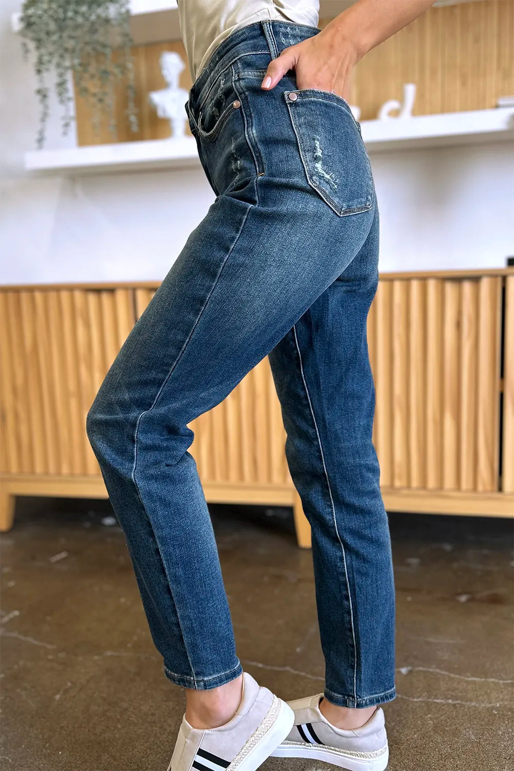Person wearing blue jeans with a blurred indoor background