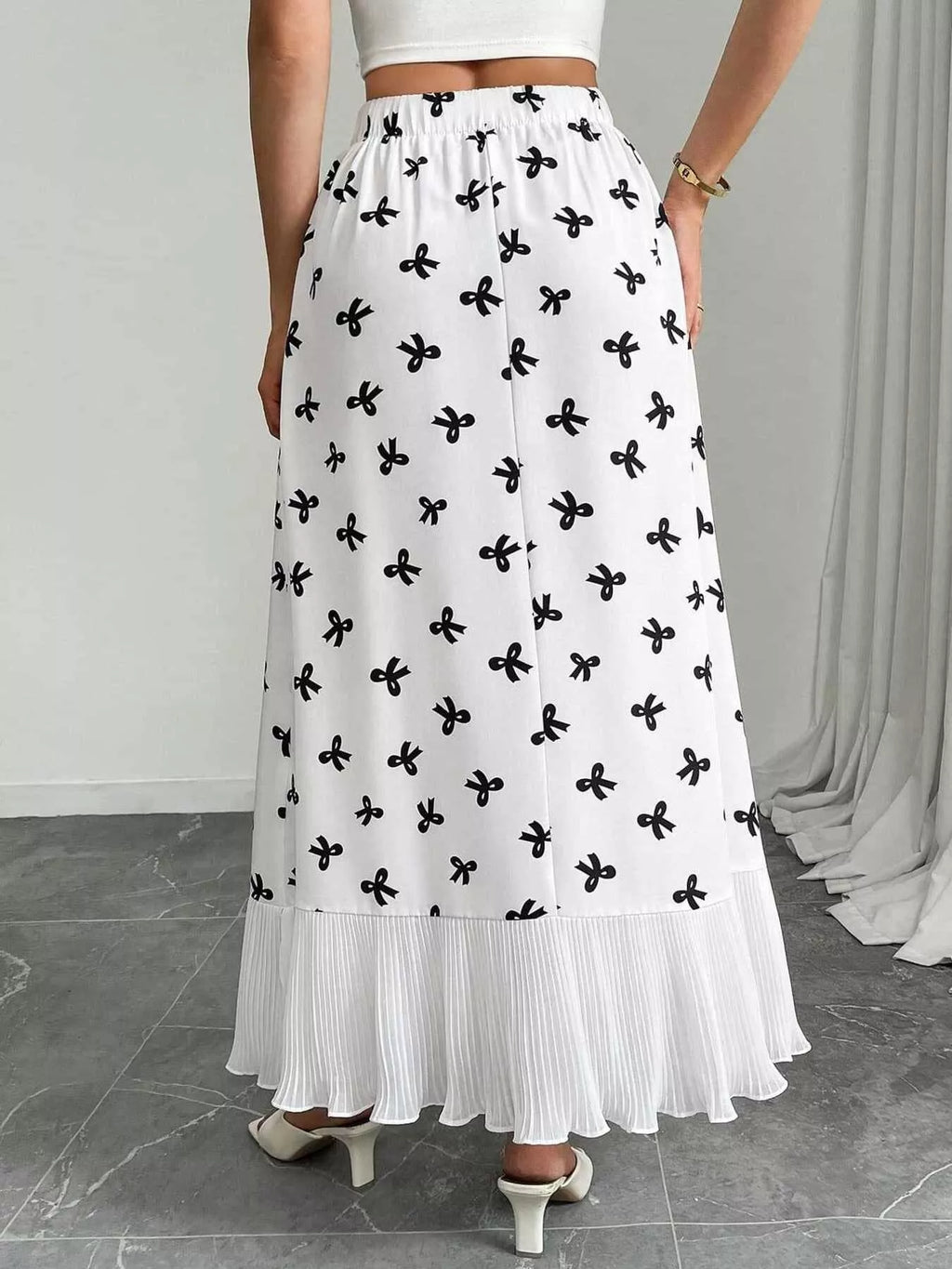 White skirt with black floral pattern worn by a person on a neutral background