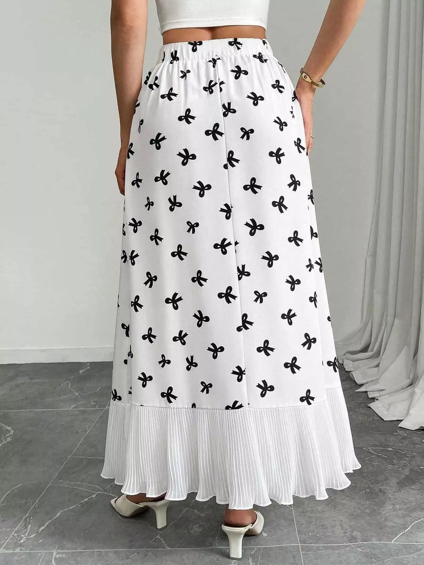 White skirt with black floral pattern worn by a person on a neutral background