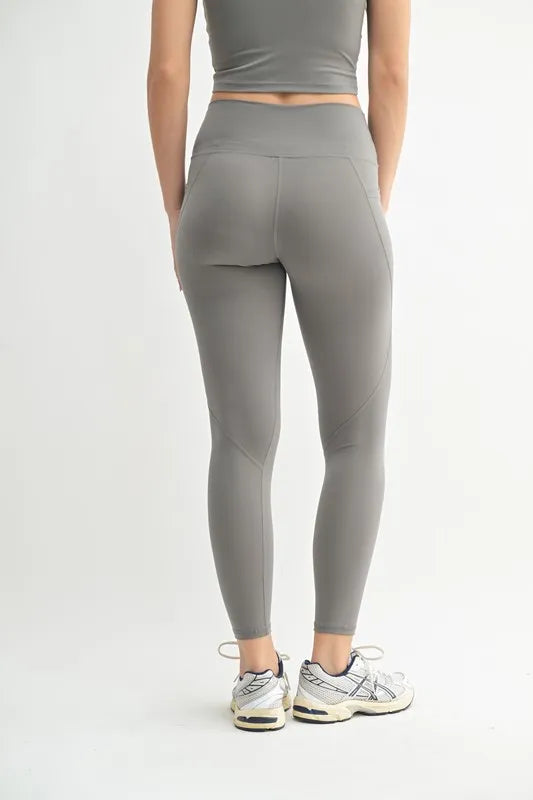 Person wearing gray leggings and a matching top on a white background