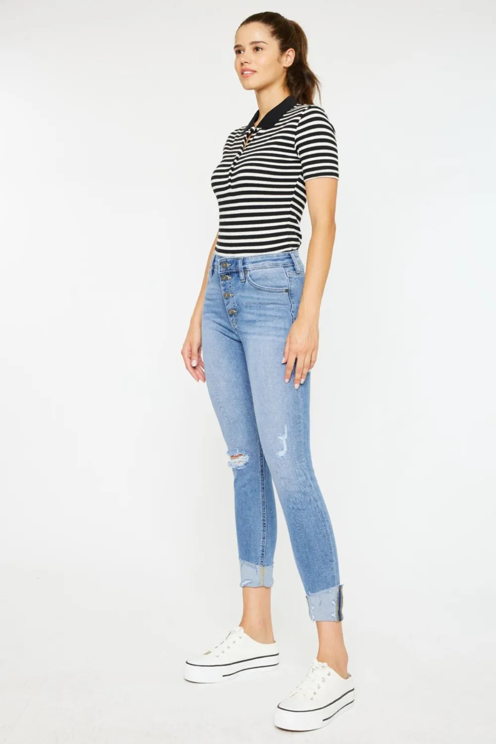 Woman wearing a striped shirt and light blue jeans on a white background