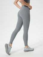 Person wearing gray leggings and matching sneakers on a white background