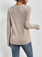 Person wearing a beige ribbed sweater and blue jeans against a white background