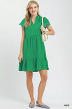 Woman wearing a green dress holding a beige handbag on a white background