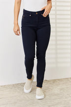 Person wearing dark blue jeans and white shoes on a neutral background
