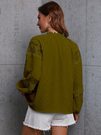 Woman wearing a green lace blouse against a gray concrete wall