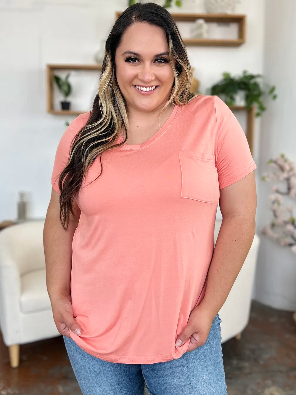 Woman wearing a pink t-shirt with a pocket in a home setting