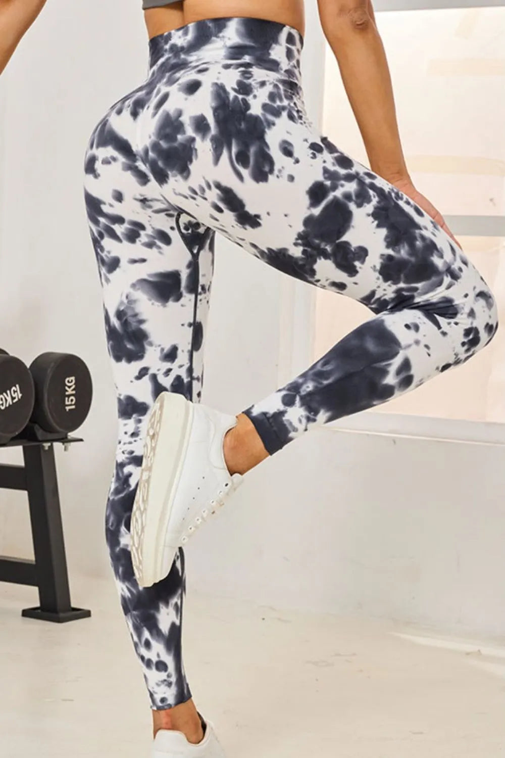 Person wearing tie-dye leggings and white sneakers in a gym setting