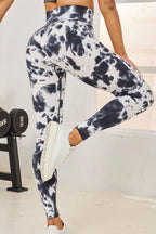 Person wearing tie-dye leggings and white sneakers in a gym setting