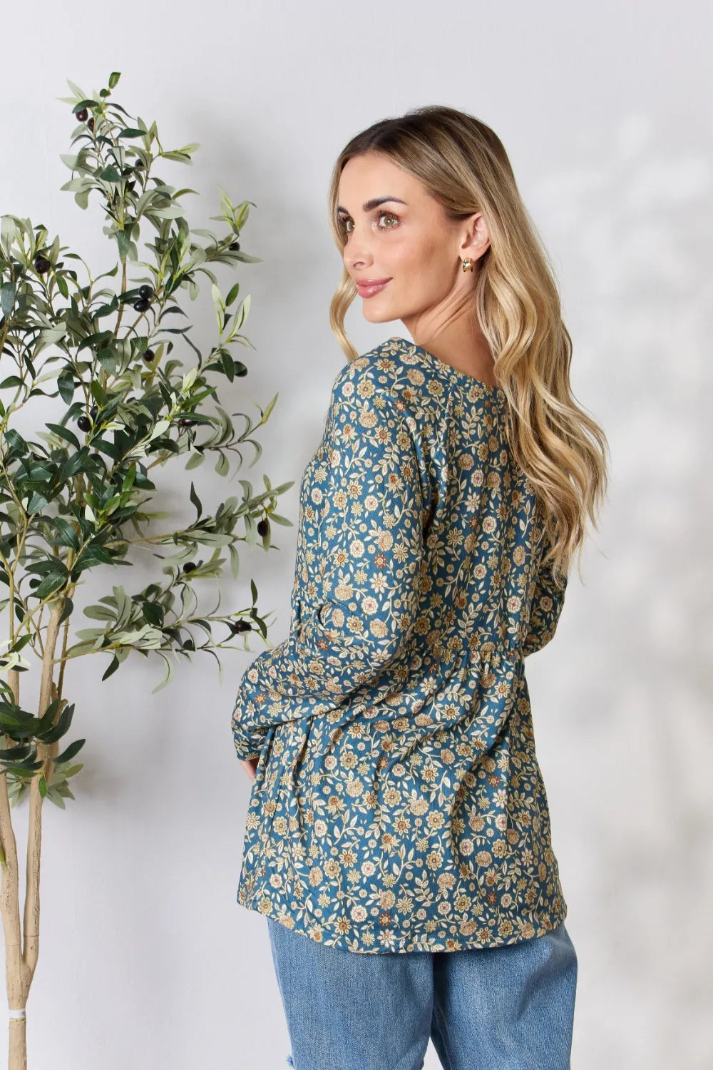 Woman wearing a floral blouse with a plant on a white background