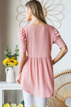 Woman wearing a pink dress standing in a room with decorative elements.