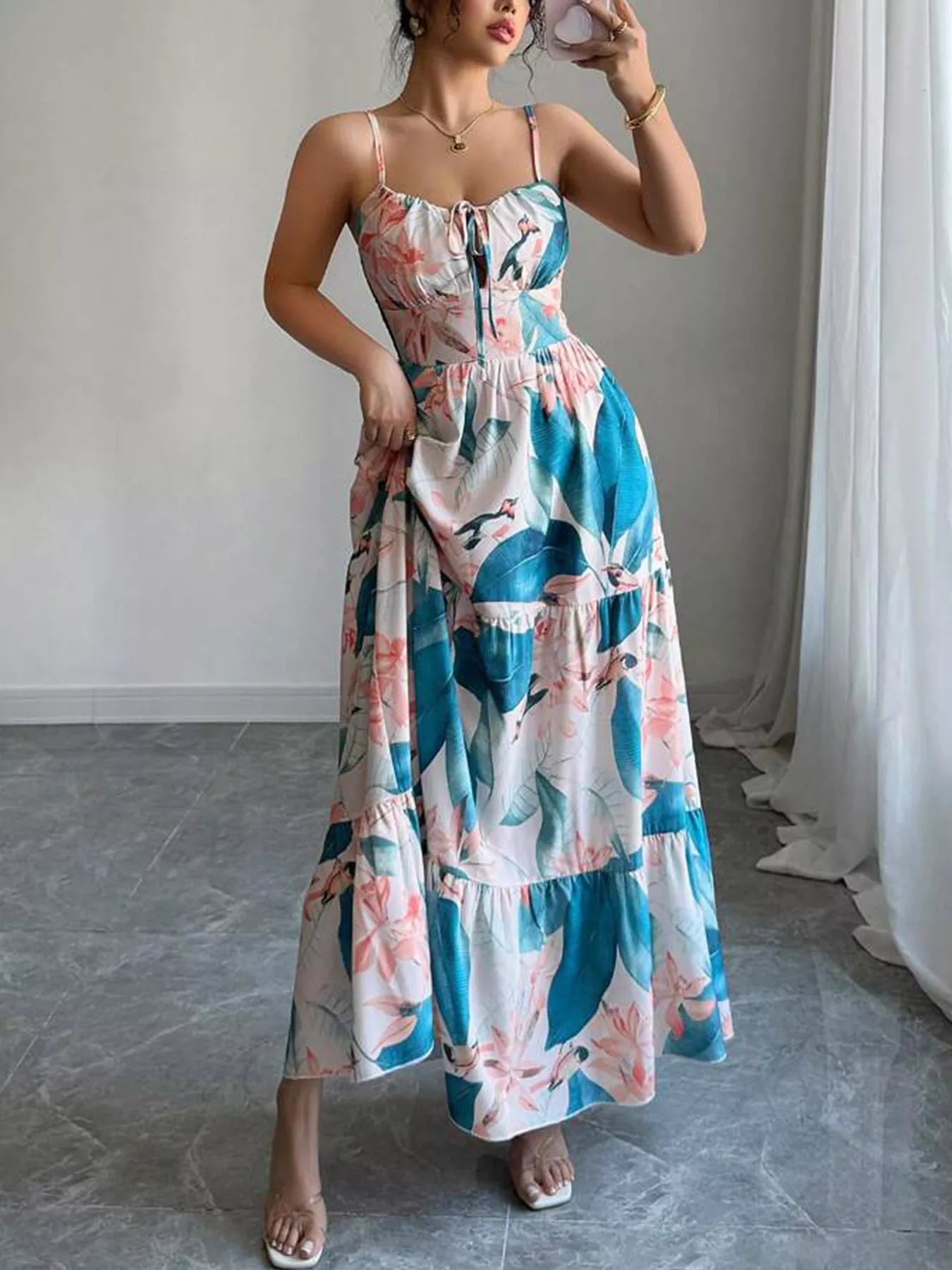Woman wearing a floral dress with blue and pink patterns in a minimalistic room.