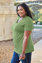 Woman wearing a green shirt standing outdoors with a blurred background
