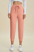 Person wearing pink sweatpants and white sneakers on a beige background