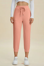 Person wearing pink sweatpants and white sneakers on a beige background