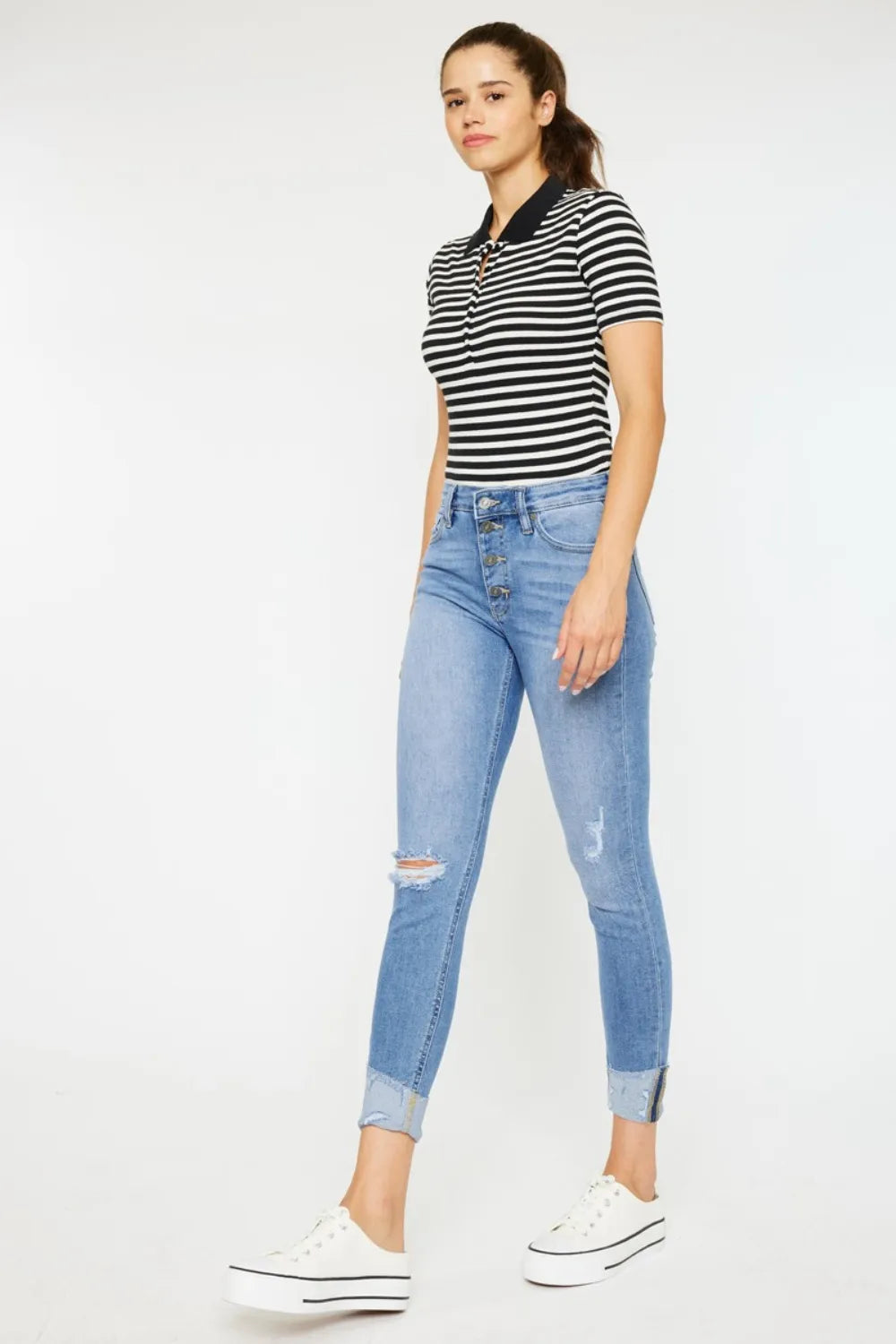 Woman wearing a striped shirt and light blue jeans on a white background