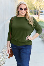 Woman wearing a green top and blue jeans outdoors.
