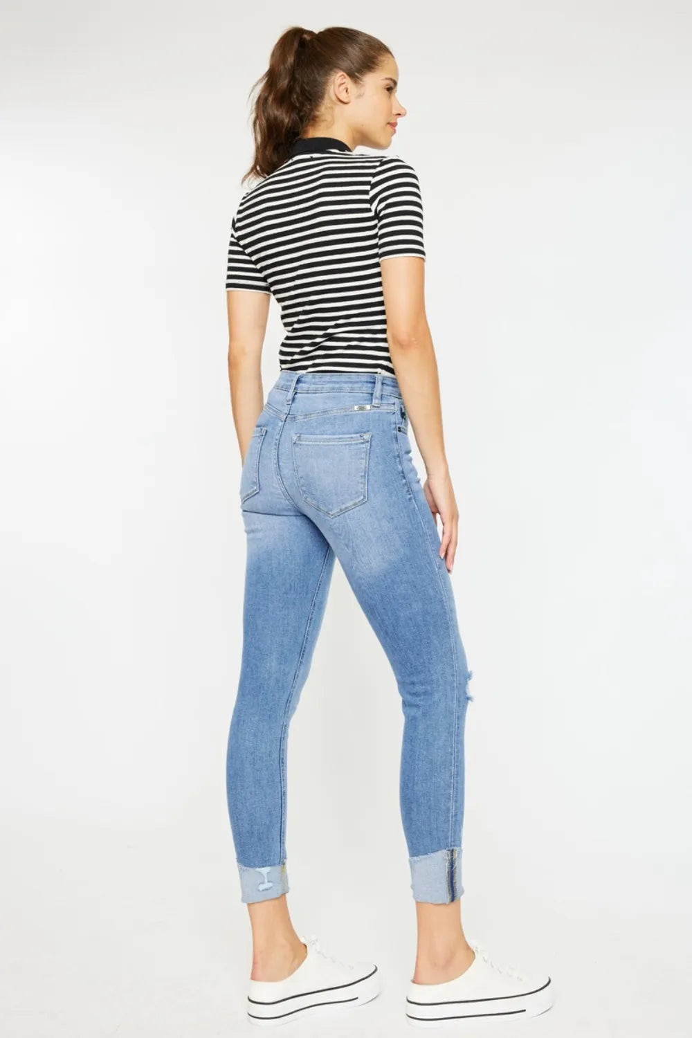 Woman wearing a striped shirt and blue jeans on a white background