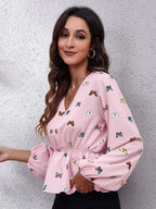 Woman wearing a pink blouse with butterfly pattern against a gray wall