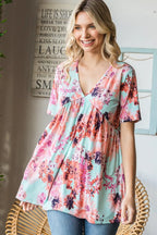 Woman wearing a floral blouse sitting on a chair with a decorative wall in the background