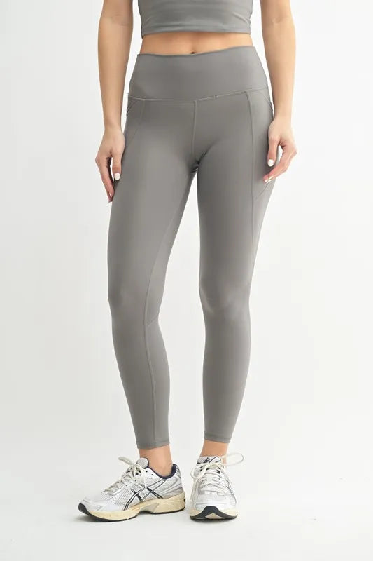 Person wearing gray leggings and a crop top on a light gray background