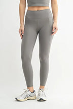Person wearing gray leggings and a crop top on a light gray background