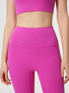 Person wearing bright pink athletic leggings and top on a light gray background