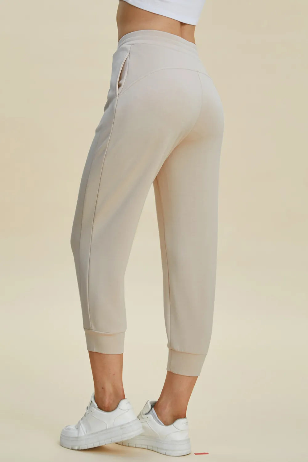 Beige jogger pants worn by a person on a beige background